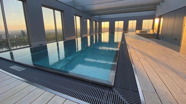 A rooftop infinity pool with a city view, large windows, and a modern architectural design. - Green High-end Apartment Close to Metro, Uno-city, E-parking, Pool, Gym, Sauna (Vienna)