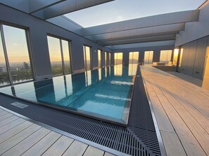 Ein Infinity-Pool auf dem Dach mit Blick auf die Stadt, großen Fenstern und einem modernen architektonischen Design.