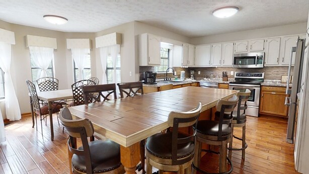 A spacious kitchen with a large island, wooden flooring, and white cabinetry.