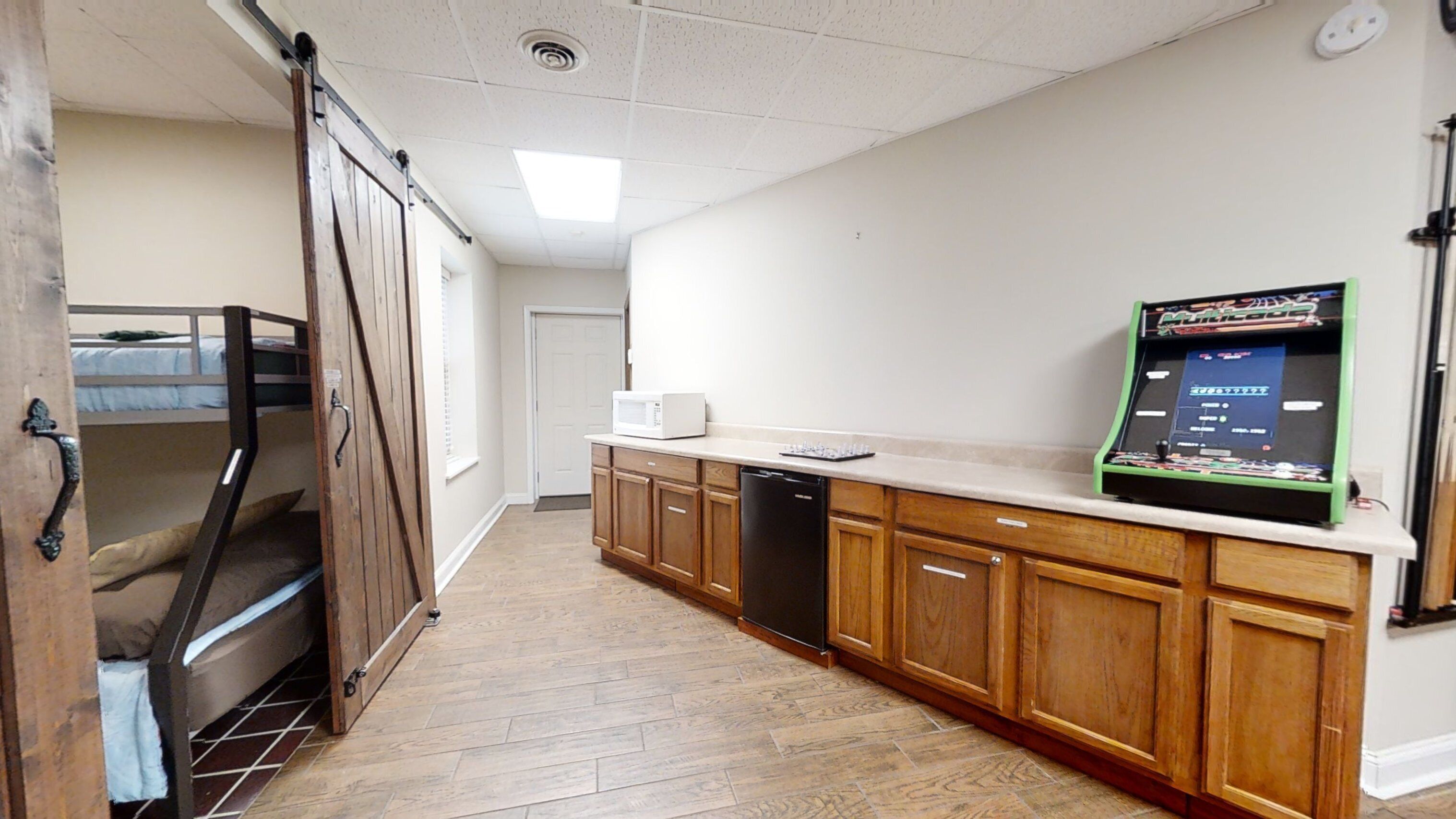 A narrow hallway with wooden cabinets, a microwave, and a vending machine.