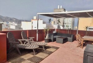 Une terrasse sur le toit avec des sièges extérieurs, une pergola et des plantes en pot.