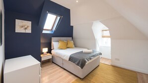 Een slaapkamer met een bed, nachtkastje en een raam.