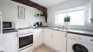 Een moderne keuken met witte kasten, een ingebouwde oven, een magnetron, een vaatwasser en een raam met uitzicht.