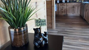 A wooden cabin interior with a potted plant, a bear figurine, and a 'Relax Cabin' sign.