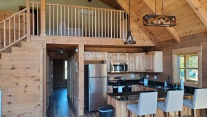 A spacious kitchen with wooden cabinets, a refrigerator, an oven, and a dining area with chairs.