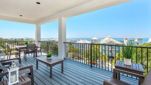 A balcony with wooden flooring, metal railings, and a view of the sea and buildings. - NEW!! Horizon! Private Beach ! Golf Cart ! Pool (Santa Rosa Beach)