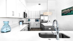 A modern kitchen with white cabinetry, stainless steel appliances, and a black sink. - NEW!! Horizon! Private Beach ! Golf Cart ! Pool (Santa Rosa Beach)