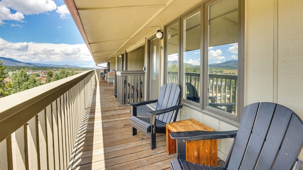 Ein Balkon mit Holzboden, zwei Adirondack-Stühlen und einem kleinen Holztisch.