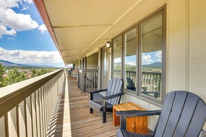 Un balcon doté d’un plancher en bois, de deux fauteuils Adirondack et d’une petite table en bois.
