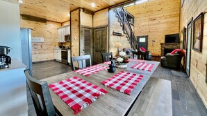 A cozy cabin interior with a dining area, kitchen, and a fireplace. - Bearly Behaving (Sevierville)