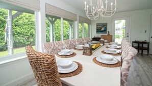 A dining area with a long table set for six, surrounded by cushioned seating. - Delightful & Modern seaside escape/Handicap Access (New London)