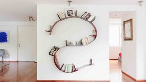 Une bibliothèque circulaire, avec des livres et des photos encadrées, est fixée à un mur blanc.