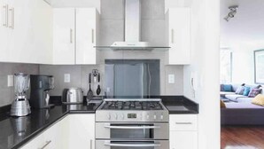 Une cuisine moderne avec des armoires blanches, une cuisinière en acier inoxydable et un four encastré.