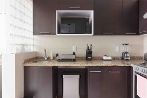 Eine moderne Küche mit dunklen Schränken, einer eingebauten Mikrowelle, einem Gasherd, einem Toaster und einer Kaffeemaschine.
