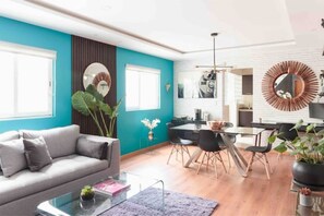 A modern living room with a grey sofa, a coffee table, and a dining area with a table and chairs.