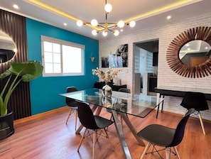 Un espace repas moderne avec une table en verre, des chaises noires et un mur d’accent bleu.