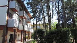 A multi-story building with balconies, surrounded by trees and greenery. - Welcoming Apartment Near the Beach (San Michele al Tagliamento)