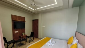 Una habitación de hotel con cama, escritorio, silla, televisor y luz en el techo.