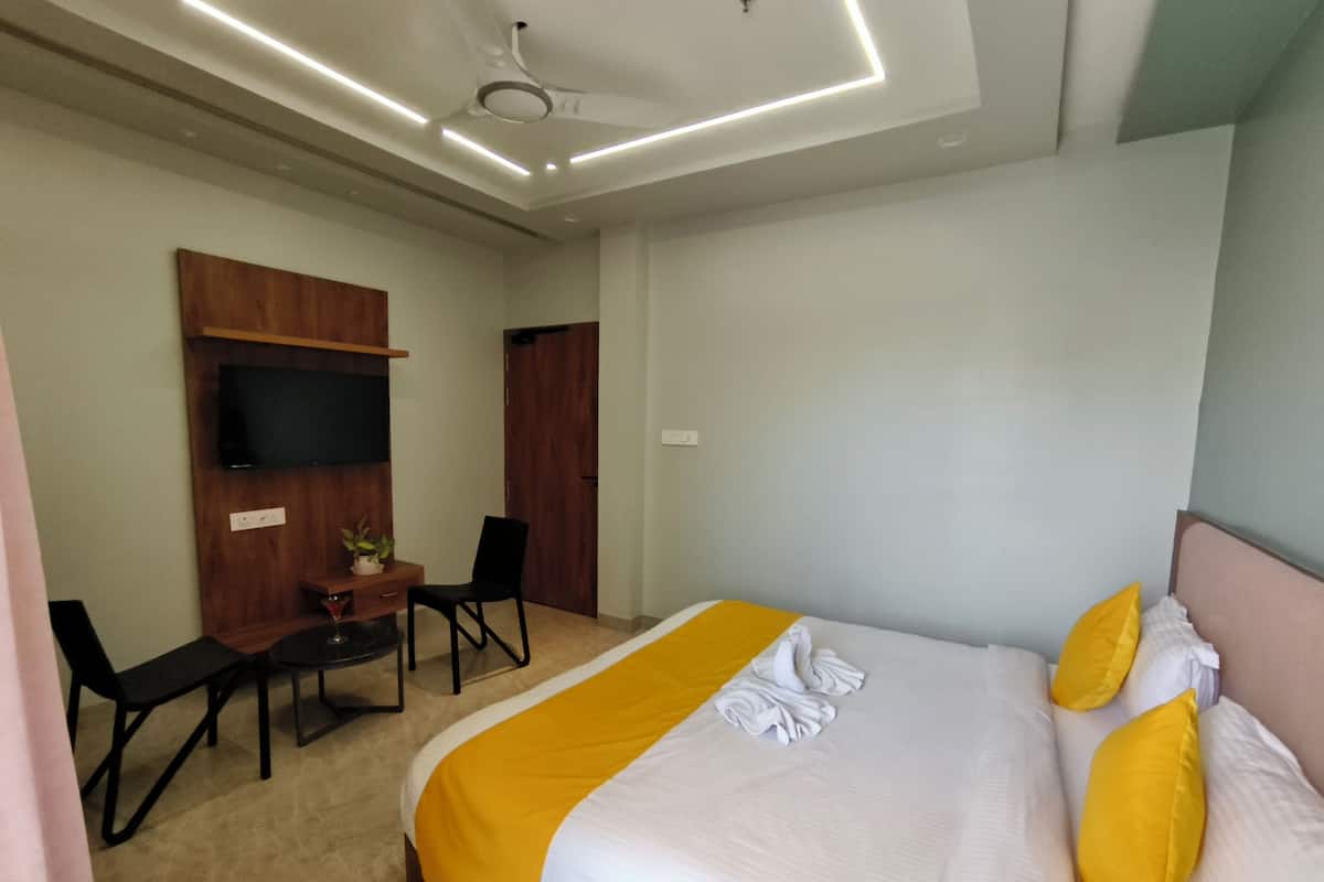 Une chambre d’hôtel équipée d’un lit, d’un bureau, d’une chaise, d’une télévision et d’un luminaire au plafond.