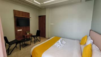 Una habitación de hotel con cama, escritorio, silla, televisor y luz en el techo.