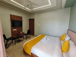 Una habitación de hotel con cama, escritorio, silla, televisor y luz en el techo.