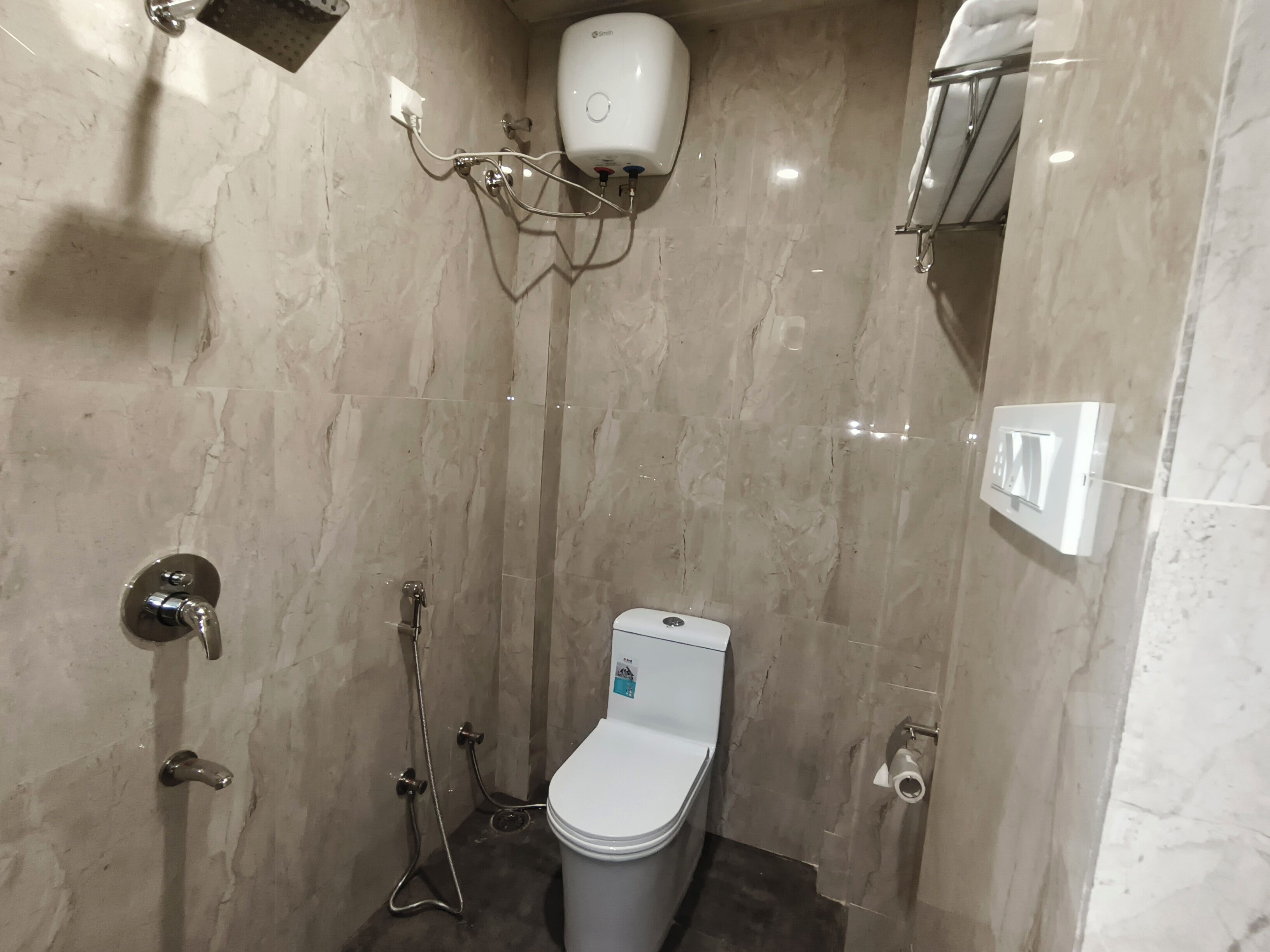 Un baño pequeño y moderno con inodoro, ducha y secamanos.