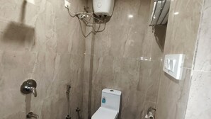 Un baño pequeño y moderno con inodoro, ducha y secamanos.
