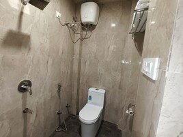 Un baño pequeño y moderno con inodoro, ducha y secamanos.