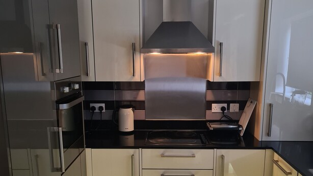 A modern kitchen with stainless steel appliances, wooden flooring, and a central island.