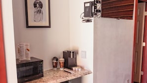 A compact kitchen with a microwave, coffee maker, and a trash bin. - Big Medicine Cabins (St. Ignatius)