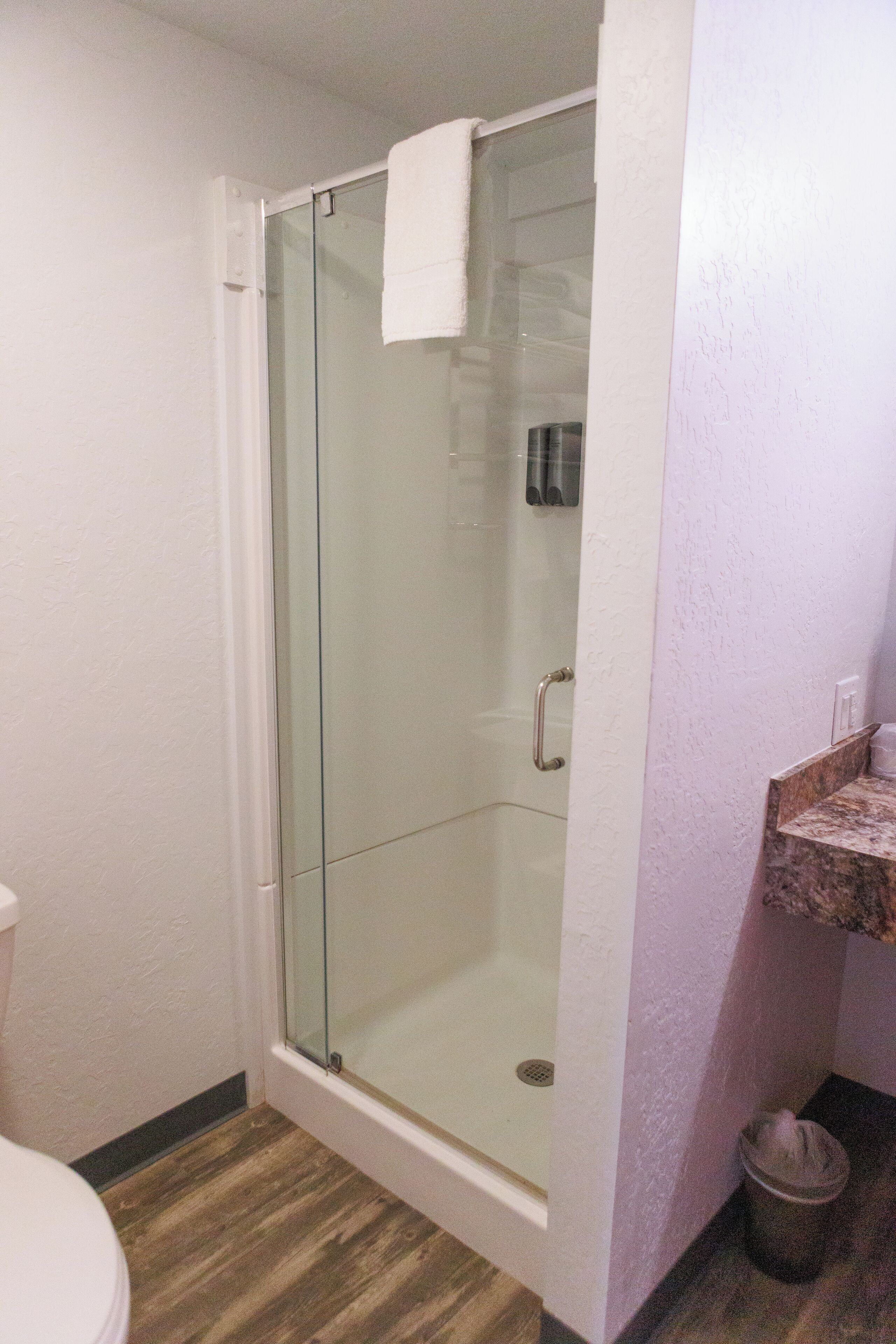 A bathroom with a glass-enclosed shower, a white toilet, and a marble sink.