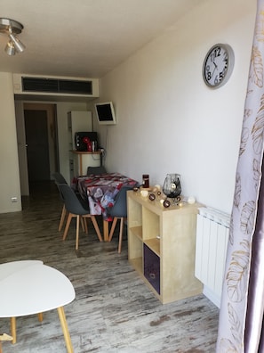 Un espacio habitable compacto con comedor, una pequeña mesa, un reloj y un radiador.