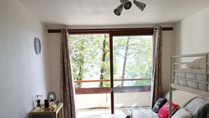 Una habitación con cama, escritorio, silla, mesa y ventana con cortinas.