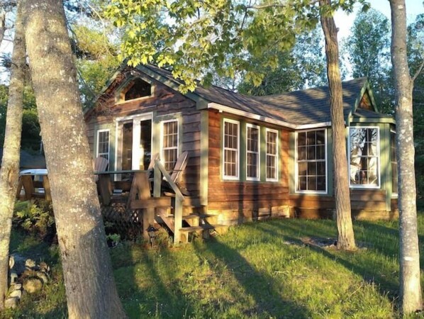 Situated in a lush environment, this cabin features a welcoming front porch and offers views of the surrounding landscape.