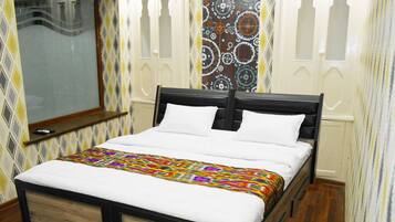 A bedroom with a bed, a window, patterned wallpaper, and wooden flooring.