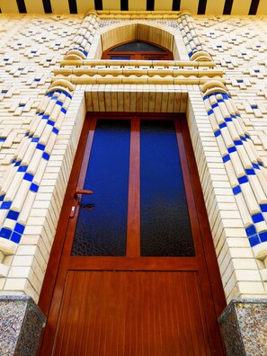 A building entrance with a wooden door and a tiled facade. - Colibri Traditional Hotel  (Samarkand)