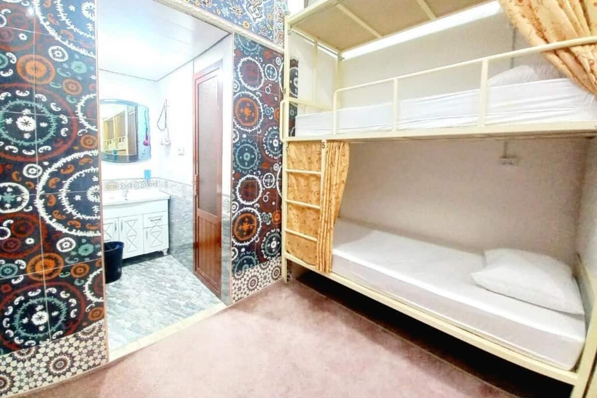 Une chambre avec un lit superposé, des murs à motifs, un lavabo et un miroir.