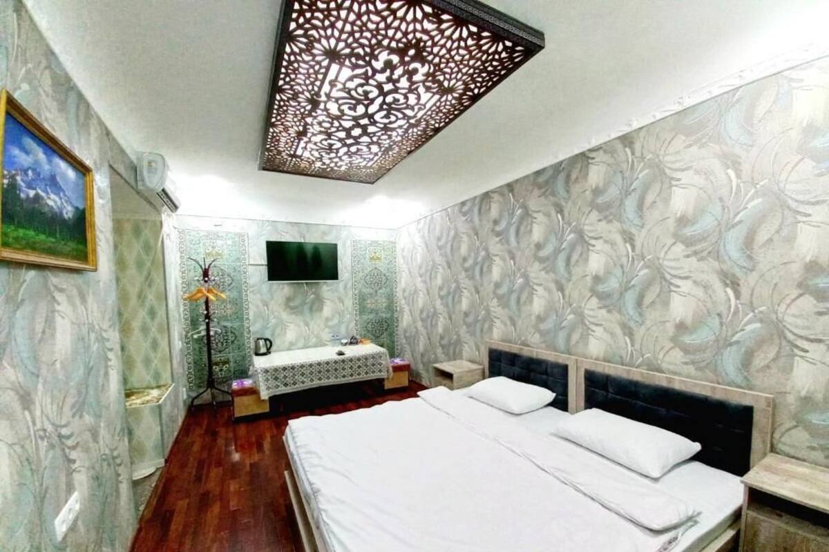 Une chambre à coucher avec un lit, une coiffeuse avec un miroir et un téléviseur fixé au mur.