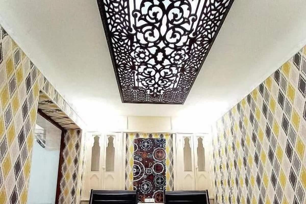 Une chambre avec deux lits, un plafond décoratif, un papier peint à motifs et un plancher en bois.