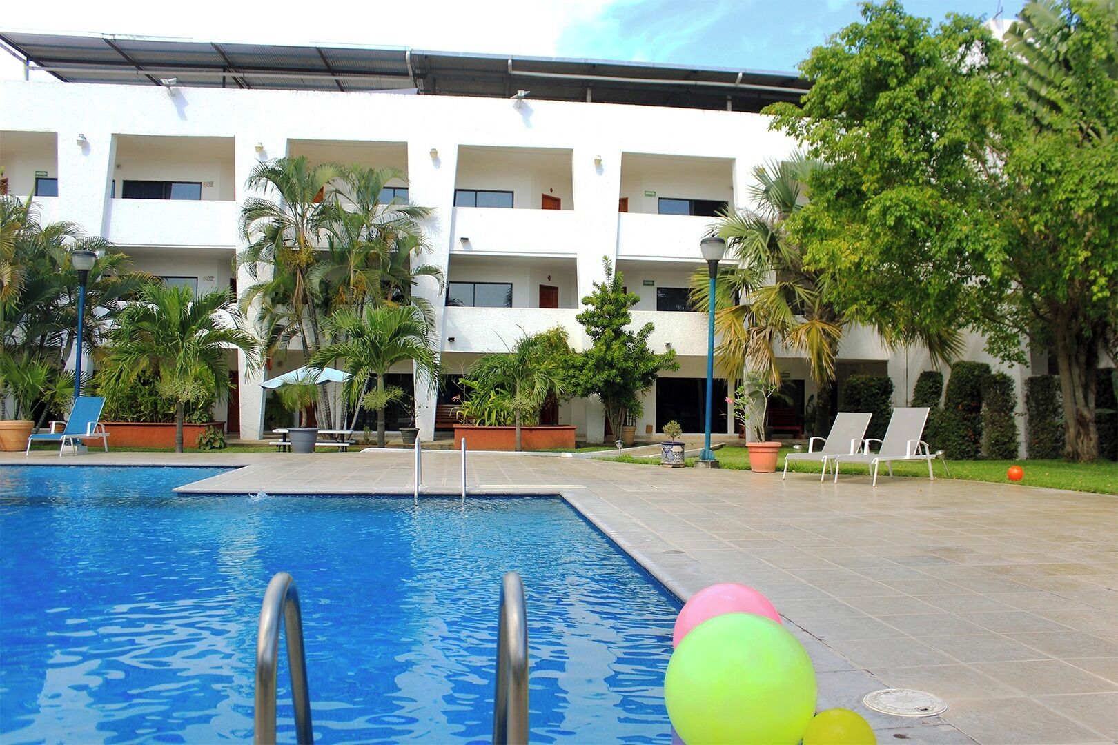 A swimming pool with lounge chairs and potted plants.