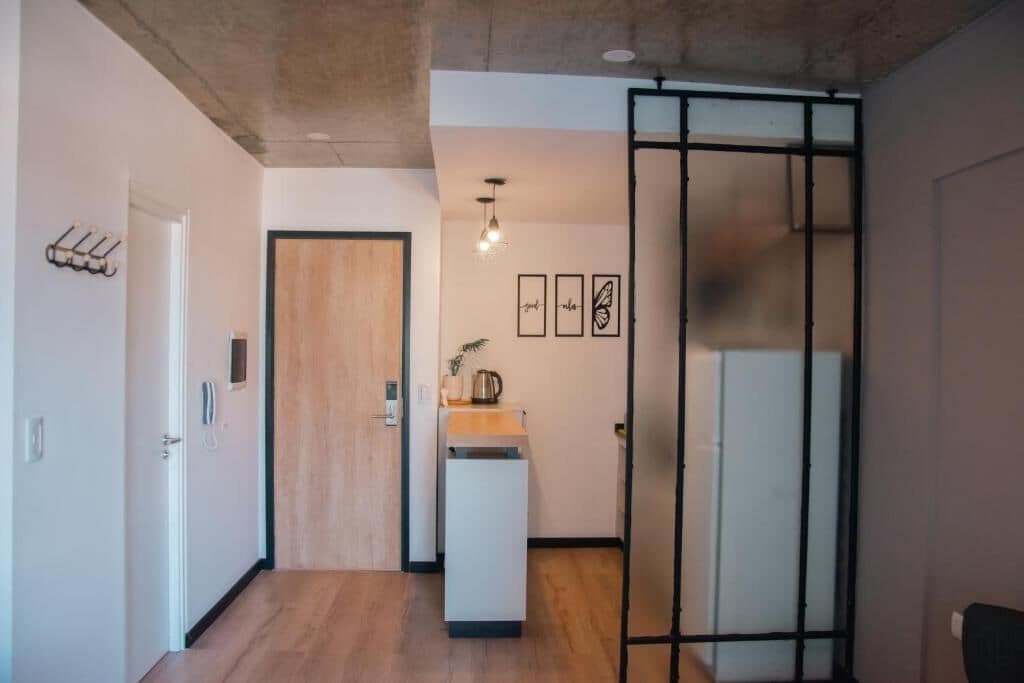 A modern kitchen with a wooden door, a small countertop, and a hanging light fixture.