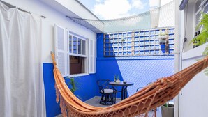 A hammock in a courtyard with a blue wall, a white door, and a small table with chairs. - Casa com 4 quartos na Vila Madalena (São Paulo)