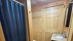 Een houten badkamer met douchegordijn, toilet en wastafel.