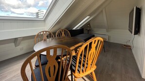 A dining area with a table and chairs, a television mounted on the wall, and a skylight. - Stunning Hilltop Nest Unparalleled Views at BnB Ap 17 (Stavanger)