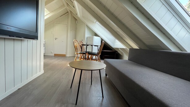 An attic room with a sofa, a table, and chairs. - Stunning Hilltop Nest Unparalleled Views at BnB Ap 17 (Stavanger)