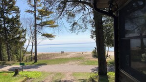 Une vue sur la plage depuis un chalet, avec une zone herbeuse et des arbres.