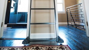 A modern interior with a central staircase, white walls, and a visible kitchen area in the background. - Beautifully restored home in Butler Tarkington Walking Distance to Butler Campus (Indianapolis)