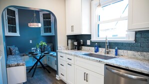 A compact kitchen with white cabinets, a built-in stove, and a window above the sink. - Beautifully restored home in Butler Tarkington Walking Distance to Butler Campus (Indianapolis)