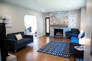 A living room with a fireplace, a blue sofa, a patterned rug, and a television.