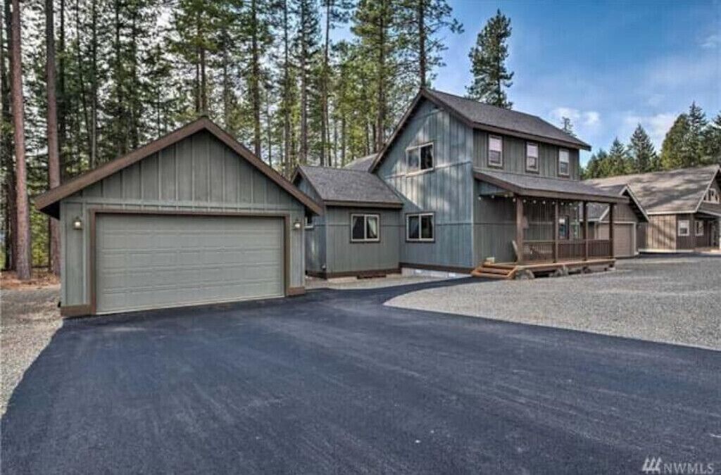 Une maison à deux étages avec un garage, une véranda et une allée.